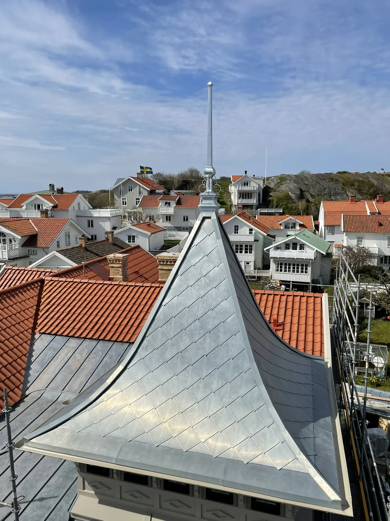 Tornhuv i plåt med hög spira sedd över stadens tak