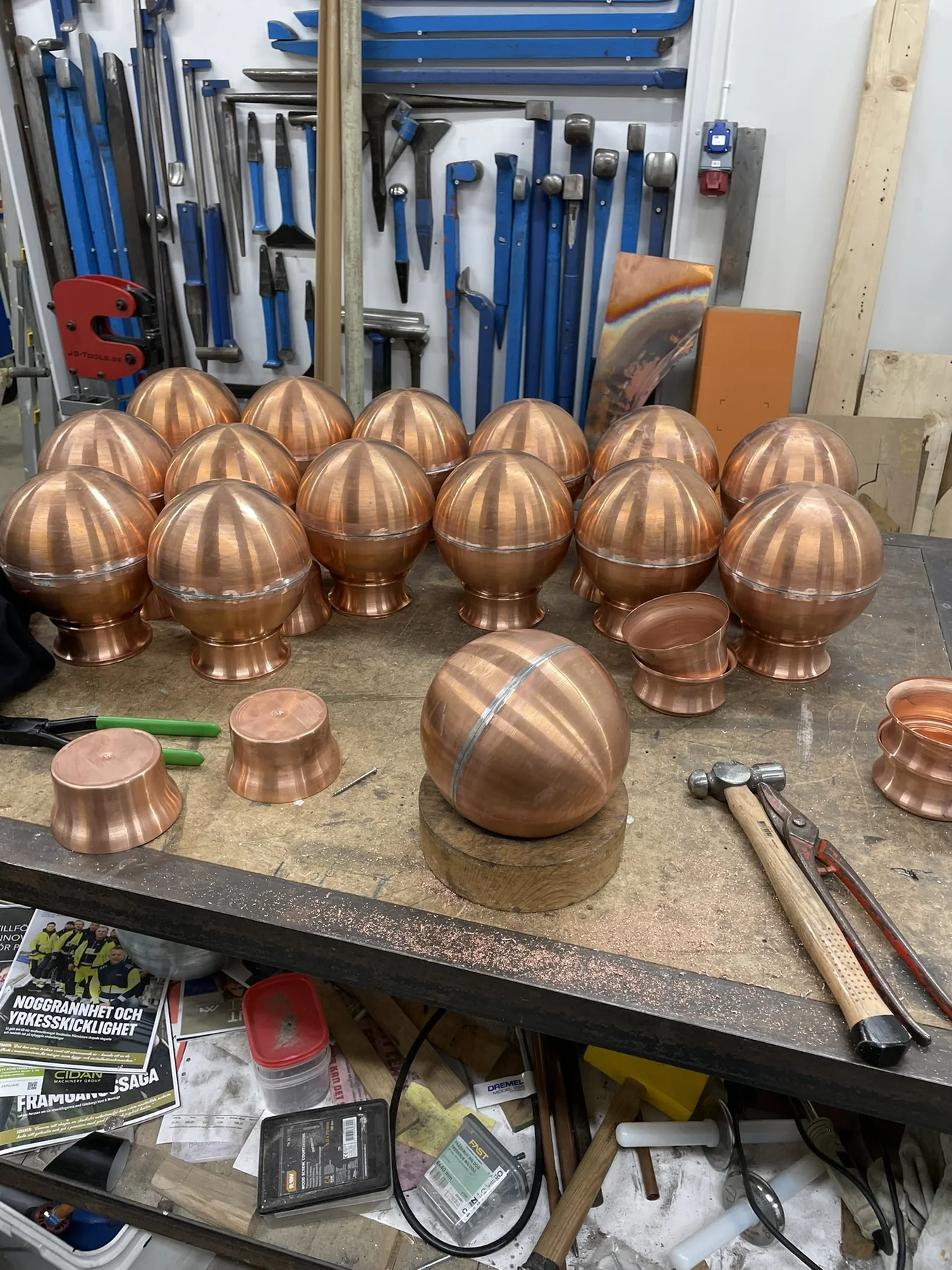 Samling handformade ornament i koppar på en arbetsbänk